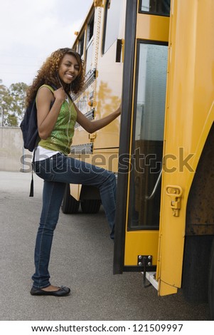 Full length of happy female student boarding school bus