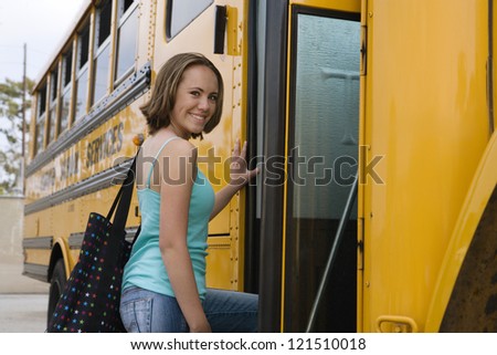 Portrait of young female student boarding school bus