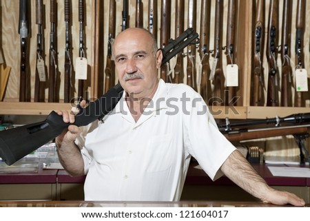 Portrait of a middle-aged man with rifle on shoulder in gun store