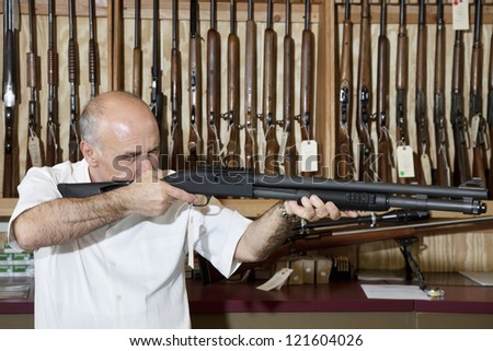 Middle-aged gun shop merchant with rifle aiming