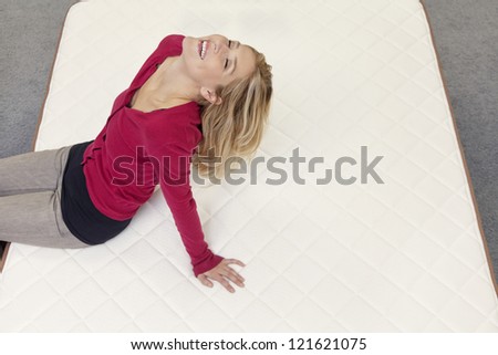 Happy woman relaxing on mattress with head back in furniture store