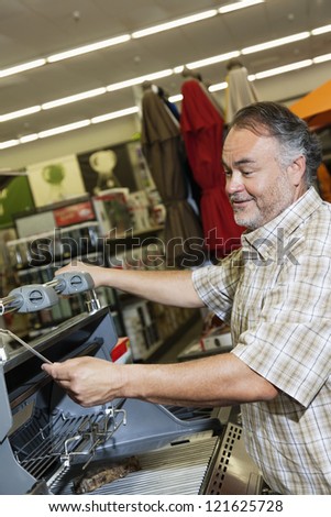 Middle-aged man looking at price tag of machinery in hardware store