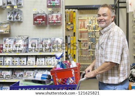 Side view portrait of a happy middle-aged man with shopping cart in hardware store