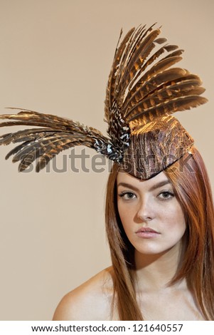 Portrait of a young woman wearing feathered headdress on colored background