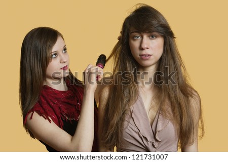 Portrait of a young female model getting her hair styled over colored background