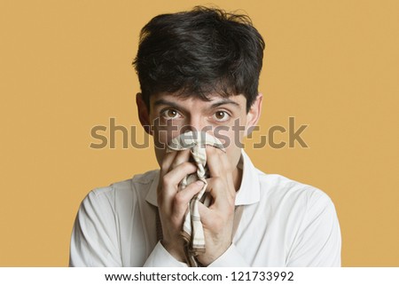 Portrait of a young man blowing nose over colored background
