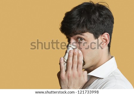 Portrait of a man blowing his nose over colored background