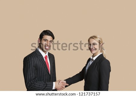 Portrait of young business people shaking hands over colored background