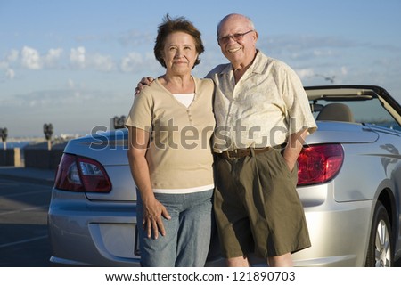 Portrait of a happy senior Caucasian couple standing together with car in the background
