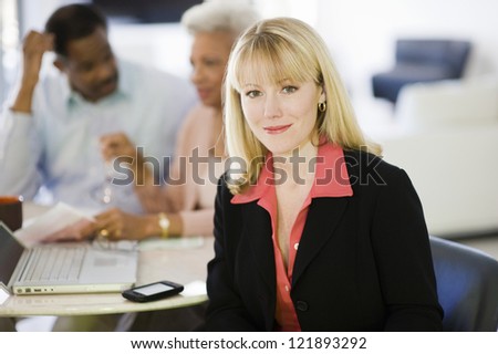 Portrait of female financial adviser smiling while senior couple sitting in background