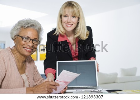 Portrait of senior African American woman being assisted by financial adviser for paperwork
