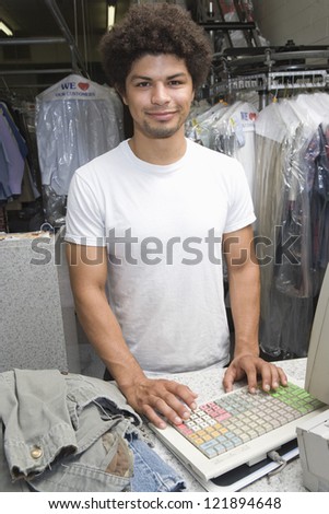 Portrait of a young mixed race man standing by checkout counter at dry cleaning store