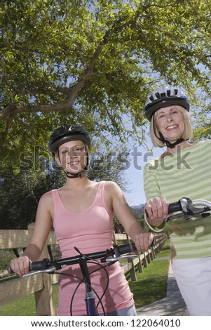 Portrait of a beautiful grandmother and granddaughter sitting on cycle wearing helmet