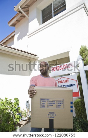 Sad man carrying cardboard box while moving out of the house