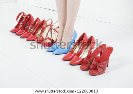 Line of red shoes with a woman standing in blue high heels