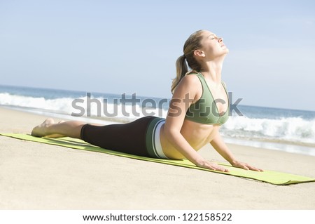 Full length of a woman in cobra pose on beach