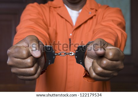 Midsection of prisoner\'s hands fettered with handcuffs