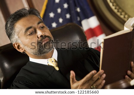 Portrait of judge sitting with book in courtroom