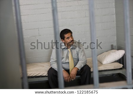 Sad businessman sitting on bed in prison
