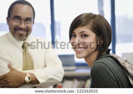 Portrait of professor and student smiling together in library