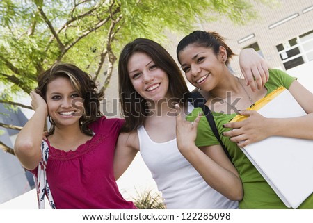 Three happy Hispanic girls standing together in college campus