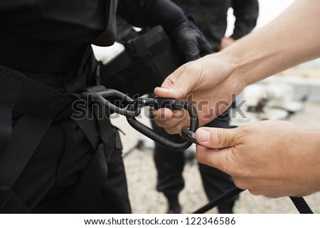 Man\'s hand fixing harness on commando\'s waist