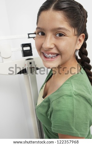 Portrait of teenage girl standing on weighing machine