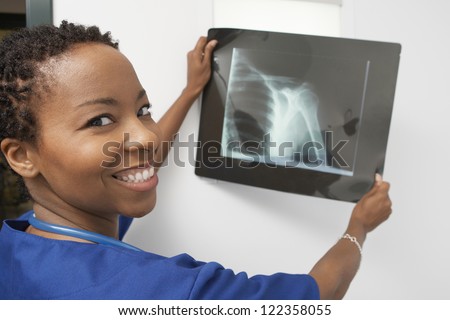 Happy female doctor examining x-ray image in hospital