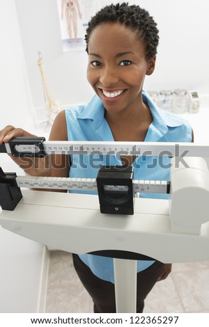 Happy African American woman adjusting scale of weighing machine