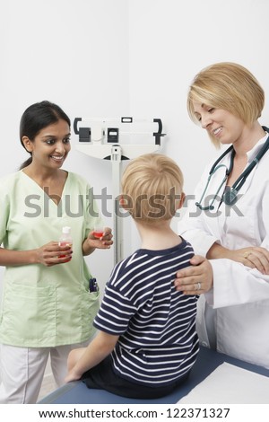 Happy doctor looking at boy while nurse standing with syrup