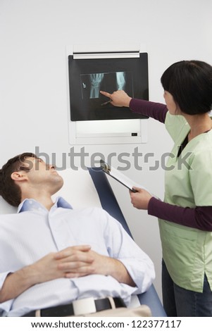 Female doctor explaining report to patient lying in bed