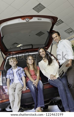 Family sitting at back of car is showroom