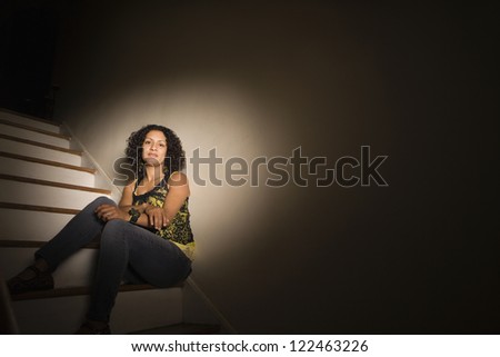 Woman sitting on steps in dark