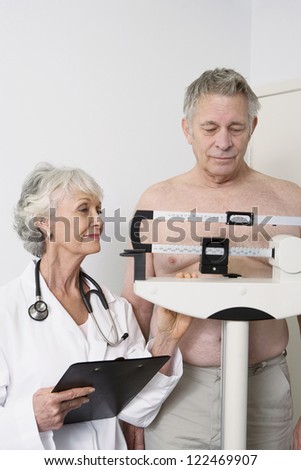 Happy senior doctor standing with patient checking weight