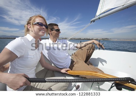 Young woman riding sailboat with man on vacations