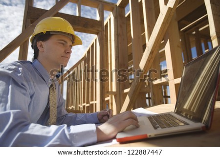 Male architect working on laptop at construction site