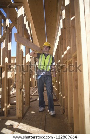 Male worker carrying wooden beam at construction site