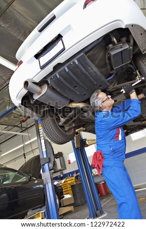 Low angle view of middle-aged mechanic working under car