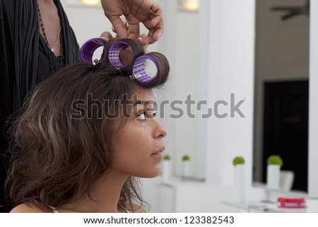 Young woman having hair curled in beauty salon