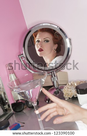 Reflection of beautiful woman in the mirror with martini glass on table