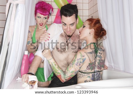 Erotic tattooed women seducing man in the bathtub