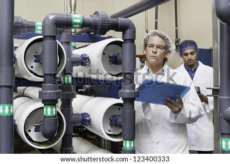 Two factory workers inspecting at bottling plant