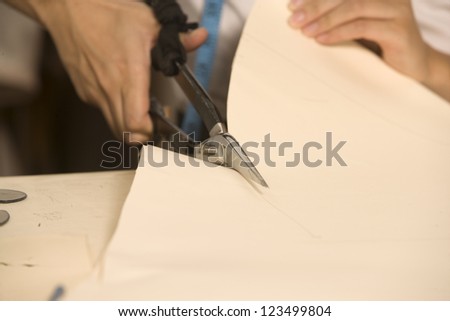 Cropped image of fashion designer cutting cloth
