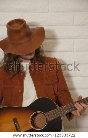 Mid adult man wearing cowboy hat and playing guitar