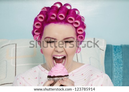 Young woman with open mouth holding cupcake