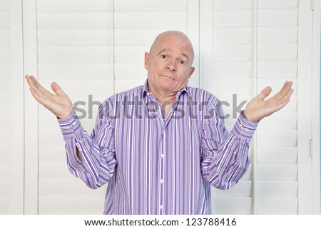 Portrait of a senior man shrugging shoulders in confusion