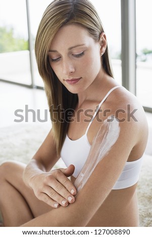 Beautiful woman applying lotion on hand