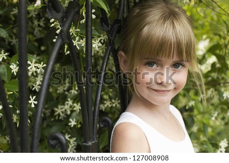 Close-up portrait of a small girl smiling in front of wrought iron gate