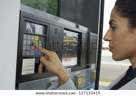 Beautiful woman pressing button of ATM machine at petrol pump
