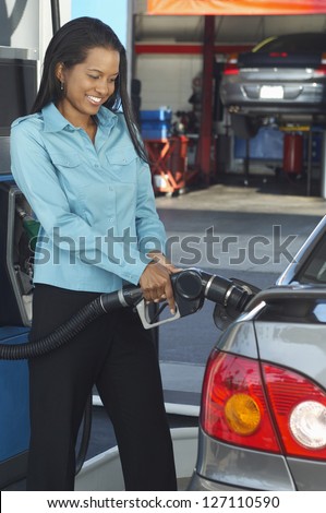 Happy african american businesswoman refueling car at petrol pump
